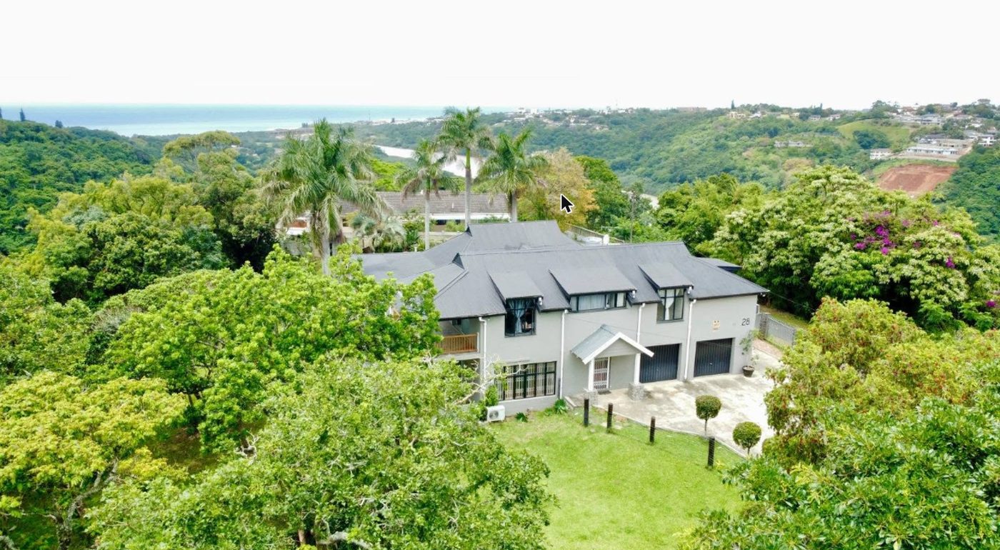 Eagle’s Roost from the air, greenery and ocean behind the house